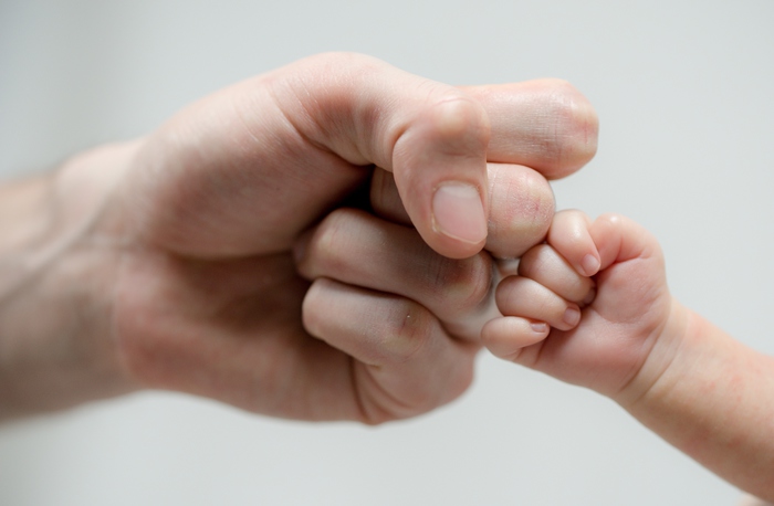 Fist of Dad and Newborn Baby